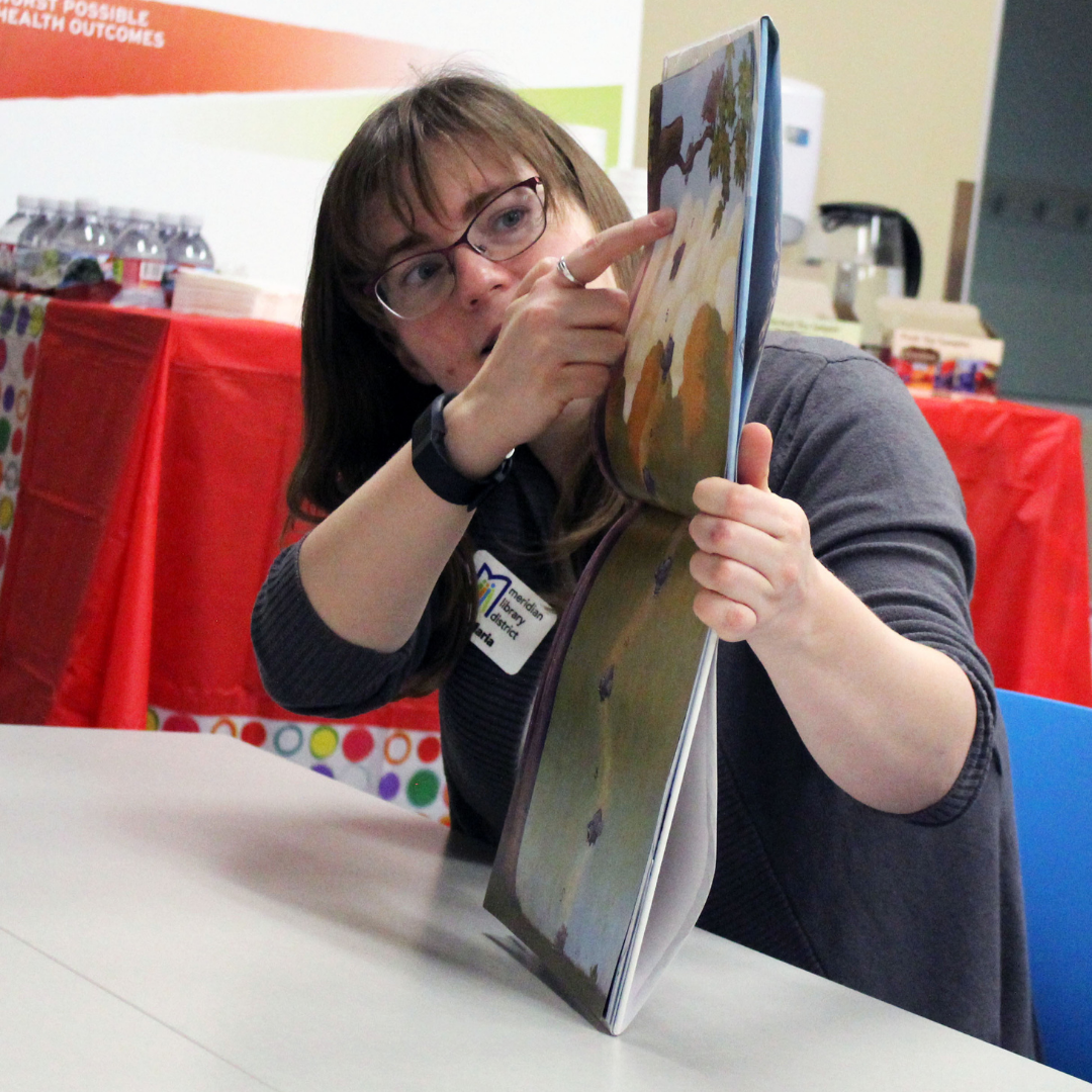 Meridian Library staff member points to a page in a picture book