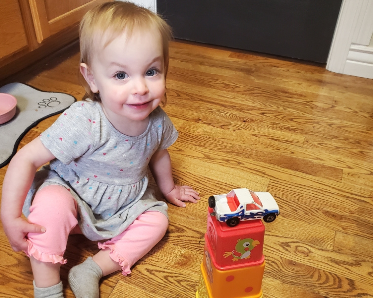 Image shows a toddler playing with stacking blocks