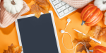 Orange background with tablet, keyboard, earbuds, pumpkins, and leaves.